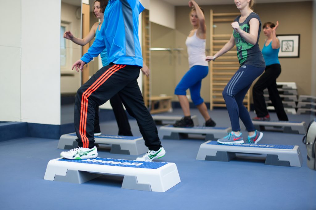 Eine Gruppe Frauen trainiert zusammen mit Ronny mit Steppern